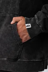 Buzo canguro negro con efecto gastado y estampa cuadrada con diseño abstracto en el pecho. Corte oversize con capucha y puños ajustados.