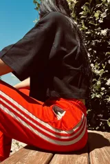 Pantalón de jogging color gris claro con cordón ajustable en la cintura y tres rayas verticales negras a los costados.