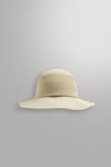 Sombrero tipo bucket color beige, confeccionado en tejido técnico con perforaciones en la copa para mejorar la transpirabilidad. Tiene ajuste elástico y ala ancha con pespuntes.