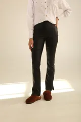 Pantalón ajustado de gabardina negro, con bolsillos traseros y abertura lateral en la pierna baja.