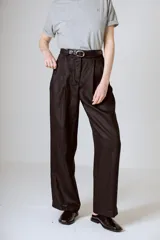 Pantalón negro de corte ancho y tiro alto, con pinzas en la cintura y bolsillos laterales.