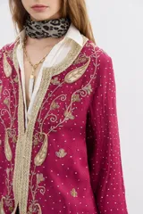 Saco largo de viscosa color fucsia con bordados dorados. Presenta un diseño con guarda bordada en el delantero, escote y puños, cuello redondo y cierre frontal con ganchos invisibles.
