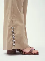 Pantalón de vestir color beige, de corte palazzo, con cintura alta y detalle de botones en el ruedo.