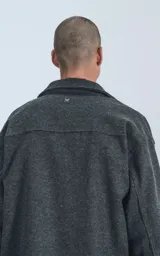 Chaqueta gris de paño con cuello clásico, cierre frontal con botones, bolsillos laterales y corte recto.
