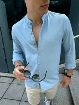 Camisa celeste de lino con cuello mao, manga larga y abotonadura frontal.
