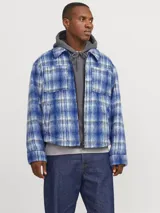 Sobrecamisa corta de manga larga con cuello sport y fit cómodo, confeccionada en tejido plano con efecto lana a cuadros azules y grises. Cuenta con cierre frontal de cremallera, puños con botones, solapa cortaviento, bolsillos en pecho y delanteros.