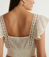 Blusa musculosa cropped color crudo, de algodón texturizado, con escote cuadrado, tirantes anchos con volantes y lastex en el dobladillo.
