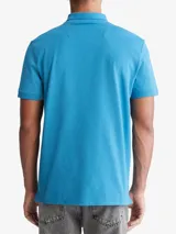 Chomba celeste de manga corta, confeccionada en mezcla de algodón y poliéster. Presenta cuello clásico con solapa de dos botones y logo de Calvin Klein bordado en el pecho.