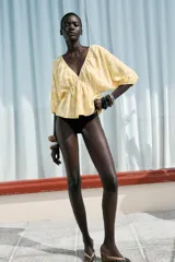 Top amarillo con estampado floral en jacquard, escote en pico, mangas cortas abullonadas con elástico, cintura elástica y espalda descubierta ajustable con lazos.