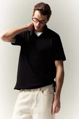 Remera polo negra de piqué de algodón, manga corta, cuello clásico con tapeta de botones y corte estándar.