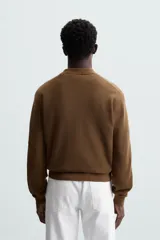 Polo marrón de corte relaxed fit, tejido en punto de algodón. Tiene cuello solapa con cierre frontal de botonadura, manga larga y acabados en rib.