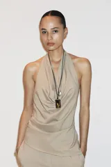 Top color beige confeccionado en algodón 100% con efecto teñido. Presenta cuello halter con lazada y escote drapeado. El bajo tiene un acabado asimétrico.
