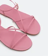 Sandalias planas plateadas con tiras finas, puntera redonda y cierre en el tobillo.