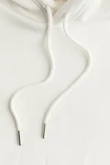 Canguro holgado color blanco, con capucha forrada con cordón ajustable, bolsillo tipo canguro, puños y bajo en punto elástico.