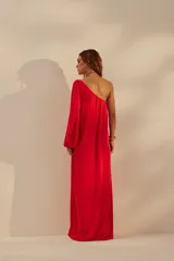 Vestido largo rojo de un solo hombro, con manga larga abullonada y tajo lateral.