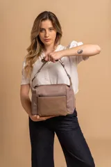 Bandolera de diseño moderno, color beige rosado, con correa regulable y bolsillo frontal con cierre.