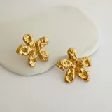 Par de caravanas doradas con forma de flor texturizada, de acero quirúrgico hipoalergénico con baño en oro de 18k.