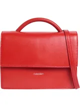Cartera de mano estructurada color rojo, con asa superior tubular y correa ajustable para cruzar. Presenta cierre desplegable con pulsador y logo metálico grabado de Calvin Klein en el frente.