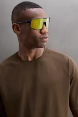 Camiseta deportiva marrón con estructura perforada, cuello redondo, manga corta y logo estampado.