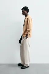 Sweater color arena con textura jaspeada, de corte recto, cuello redondo y mangas largas con terminaciones acanaladas.