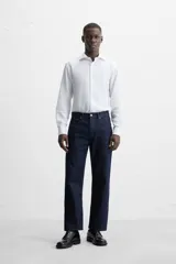 Camisa blanca de corte regular, cuello italiano, manga larga con puños abotonados y cierre frontal con botones.