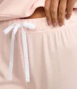 Conjunto de pijama largo color rosa claro, compuesto por un buzo de cuello redondo y un pantalón con lazo en la cintura.