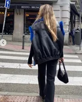 Chaleco negro de cuero sintético con cuello y sisas de piel sintética azul. Diseño holgado con elástico en la cintura.