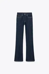 Pantalón de jean azul oscuro, de tiro medio, corte bootcut y largo hasta el tobillo. Tiene cinco bolsillos, trabillas en la cintura y cierre frontal con cremallera y botón metálico.