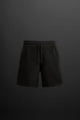 Bermuda jogger negra confeccionada en tejido de algodón con interior de rizo, cintura elástica ajustable con cordón y bolsillos laterales.