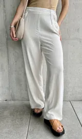 Pantalón de lino color crudo, de corte ancho y largo, con botones decorativos en la cintura.
