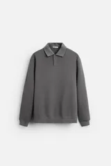 Polo manga larga gris con cuello solapa y cierre frontal de botonadura.