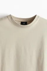 Remera color beige de algodón pesado, corte holgado, cuello redondo ribeteado, hombros caídos y bajo recto.