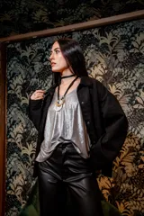 Chaqueta negra de gamuza con cuello camisero, cierre frontal con botones y bolsillos laterales.