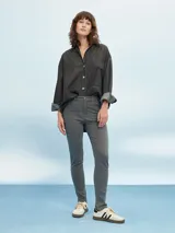 Pantalón jean skinny gris claro, tiro medio, con bolsillos delanteros y traseros.