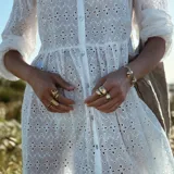 Brazalete rígido dorado con forma de caracola en los extremos.