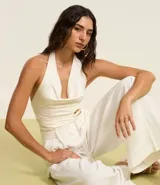 Pantalón de vestir blanco, de corte palazzo, con trabillas en la cintura, bolsillos laterales y pliegues delanteros.