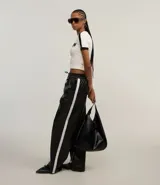 Pantalón pantalona de cuero sintético negro con cintura elástica, lazo ajustable y raya lateral blanca.