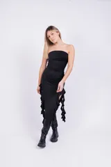 Vestido midi negro sin mangas, con escote strapless y volados asimétricos en el ruedo.