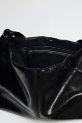 Bolso shopper marrón de efecto acharolado con asa de hombro ajustable, bolsillo interior con cremallera y cierre magnético.