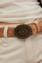 Cinturón de ante negro con hebilla metálica ovalada de estilo western, con diseño grabado de flores y detalles ornamentales.