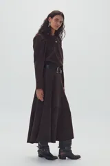Camisa marrón de gamuza con cuello redondo, mangas largas abullonadas y falda midi acampanada. Incluye cinturón ancho de cuero negro.