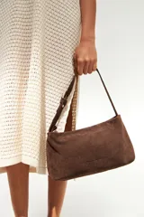 Cartera de hombro marrón de gamuza con asa corta.