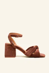 Sandalia de terciopelo color marrón, con taco cuadrado de 7 cm y tiras anudadas en la parte delantera. Cuenta con pulsera ajustable al tobillo con hebilla dorada.