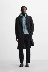 Abrigo negro regular fit confeccionado en paño con lana. Tiene cuello con solapas de muesca, manga larga, bolsillos de solapa en la cadera, bolsillo interior, abertura en el centro de la espalda y cierre frontal con botonadura.