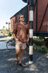 Remera tejida color crudo con cuello redondo con borde verde, mangas cortas y bolsillo en el pecho. Corte holgado.