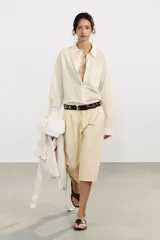 Cinturón de cuero negro con tachas plateadas, rojas y turquesas. Hebilla metálica plateada ovalada.