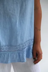 Musculosa celeste amplia y liviana confeccionada en lino italiano, con terminaciones delicadas y franja de encaje en el ruedo.