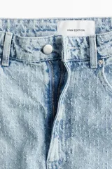 Pantalón jean de tiro bajo en denim bouclé celeste, de algodón rígido, con cinco bolsillos, cierre con botón y corte holgado con piernas amplias.
