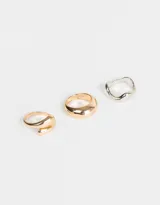 Set de tres anillos de metal, uno dorado con forma de espiral, uno dorado liso y uno plateado con forma irregular.