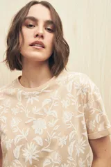 Remera blanca de manga corta con estampado floral en tonos beige.